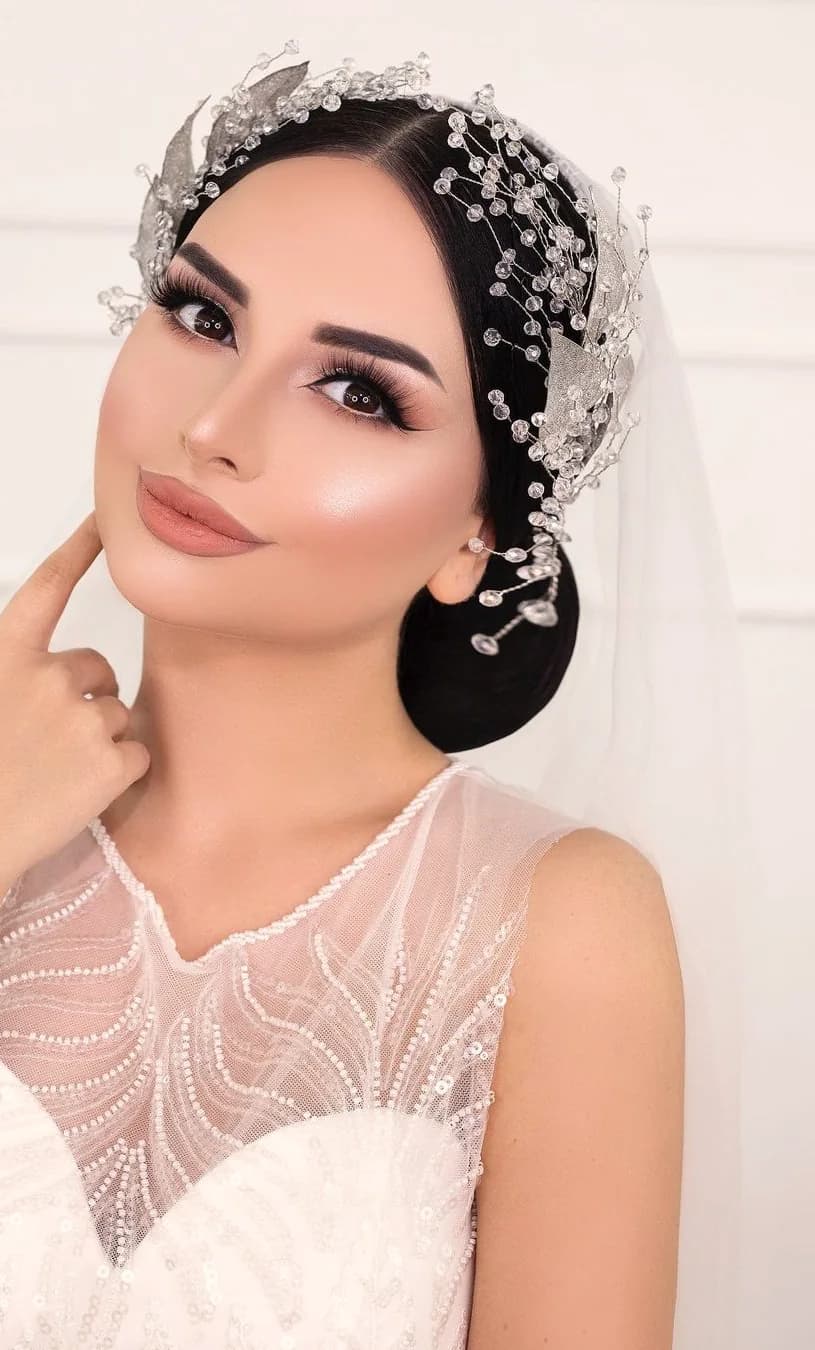 A sculpted black cap dressed with a crystal spray, over an illusion neckline