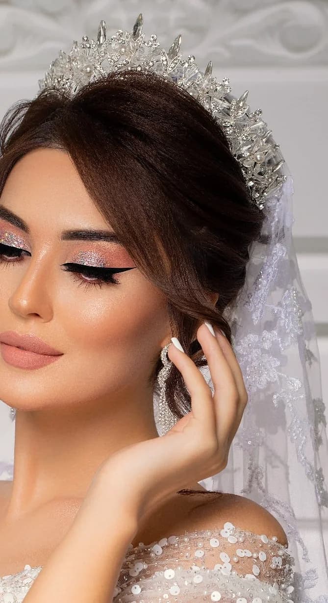 Side-set waves under a crown and a long veil, with an embroidered gown